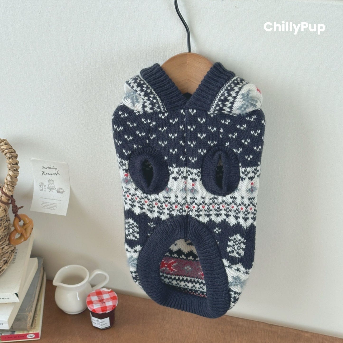 Knitted dog hoody with reindeer pattern on a wooden surface, branded 'ChillyPup'.