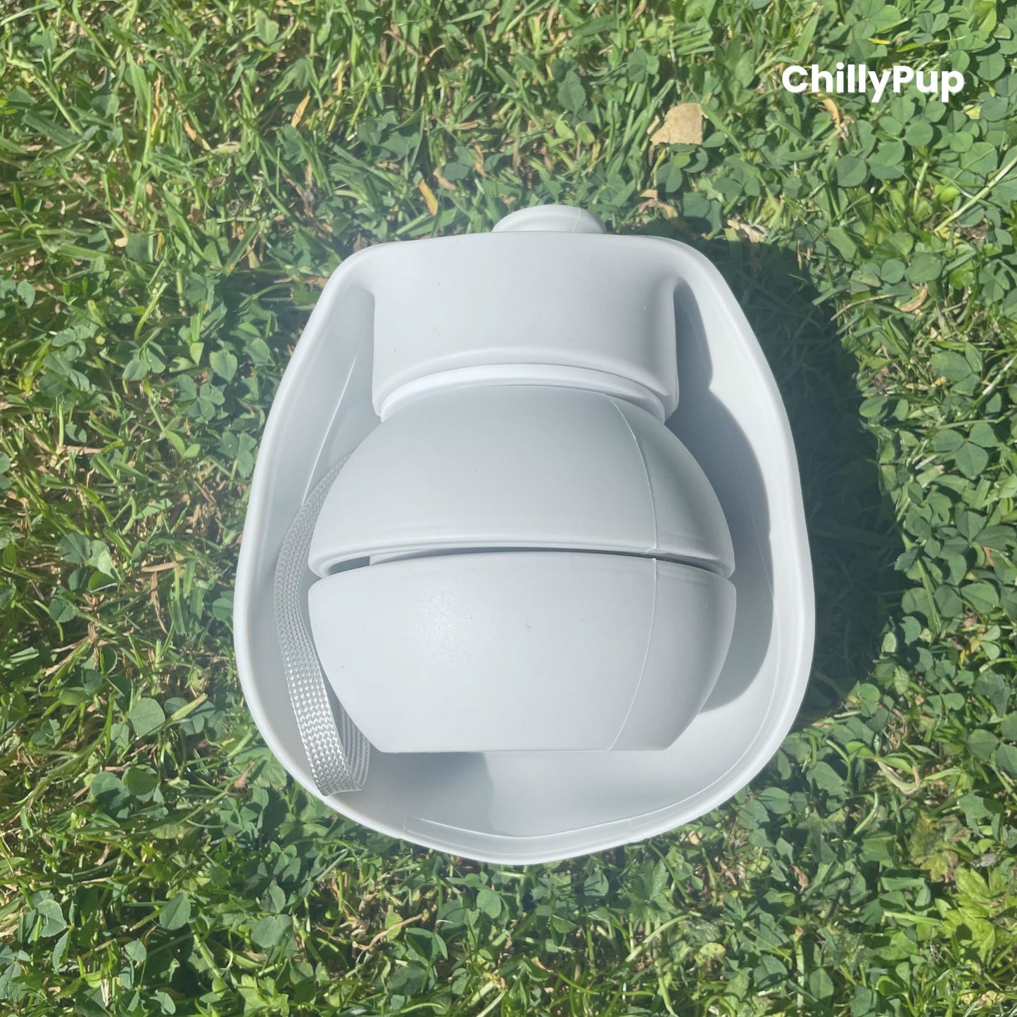 One foldable silicone water bottle completely folded up on grass.